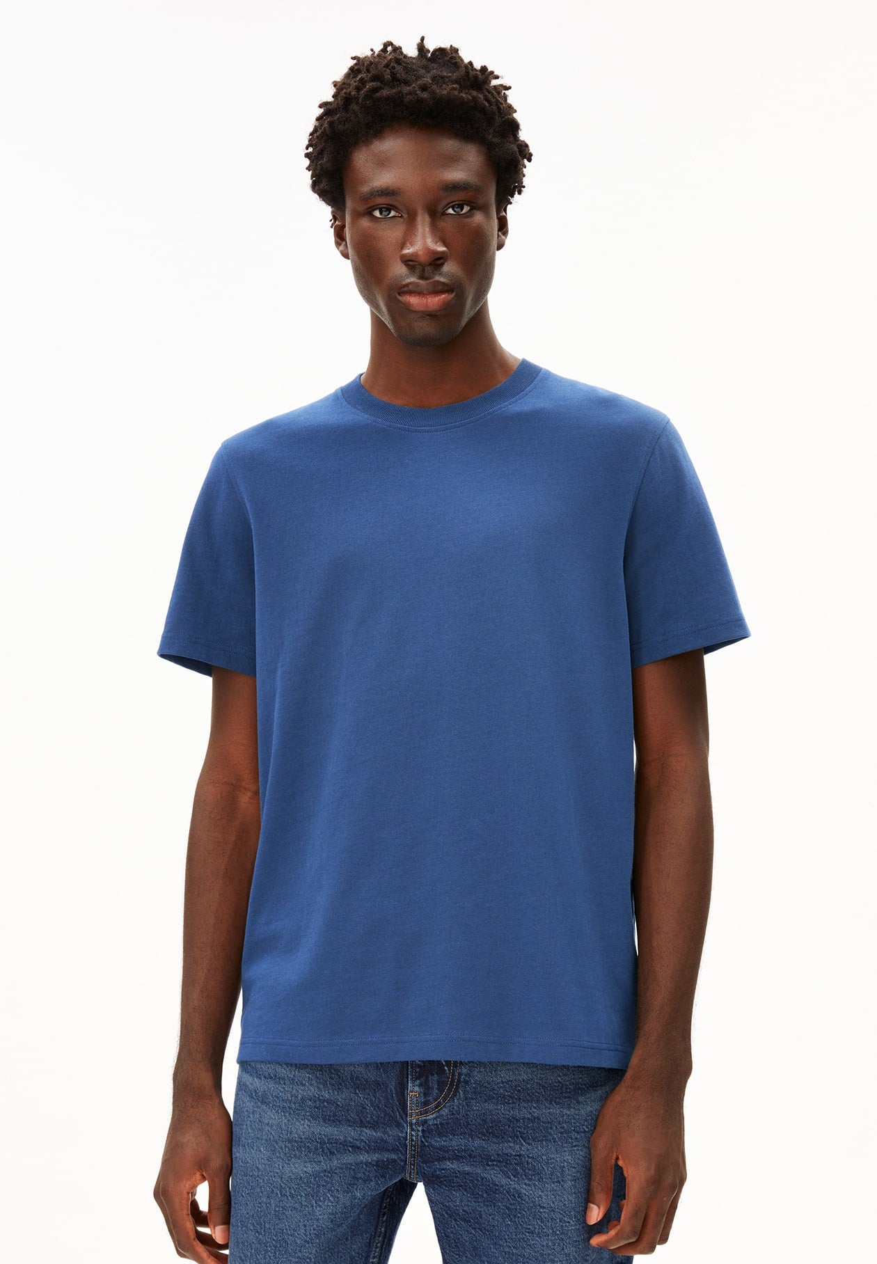 Person trägt blaues T-Shirt MAARKOS im Relaxed Fit aus Bio-Baumwolle und Jeans, frontal aufgenommen vor weißem Hintergrund.