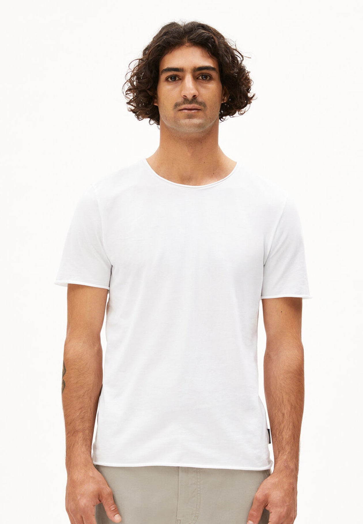 Person trägt weißes T-Shirt JAAMES BRUSHED im Regular Fit aus gebürsteter Bio-Baumwolle und beige Hose, frontal aufgenommen vor weißem Hintergrund.
