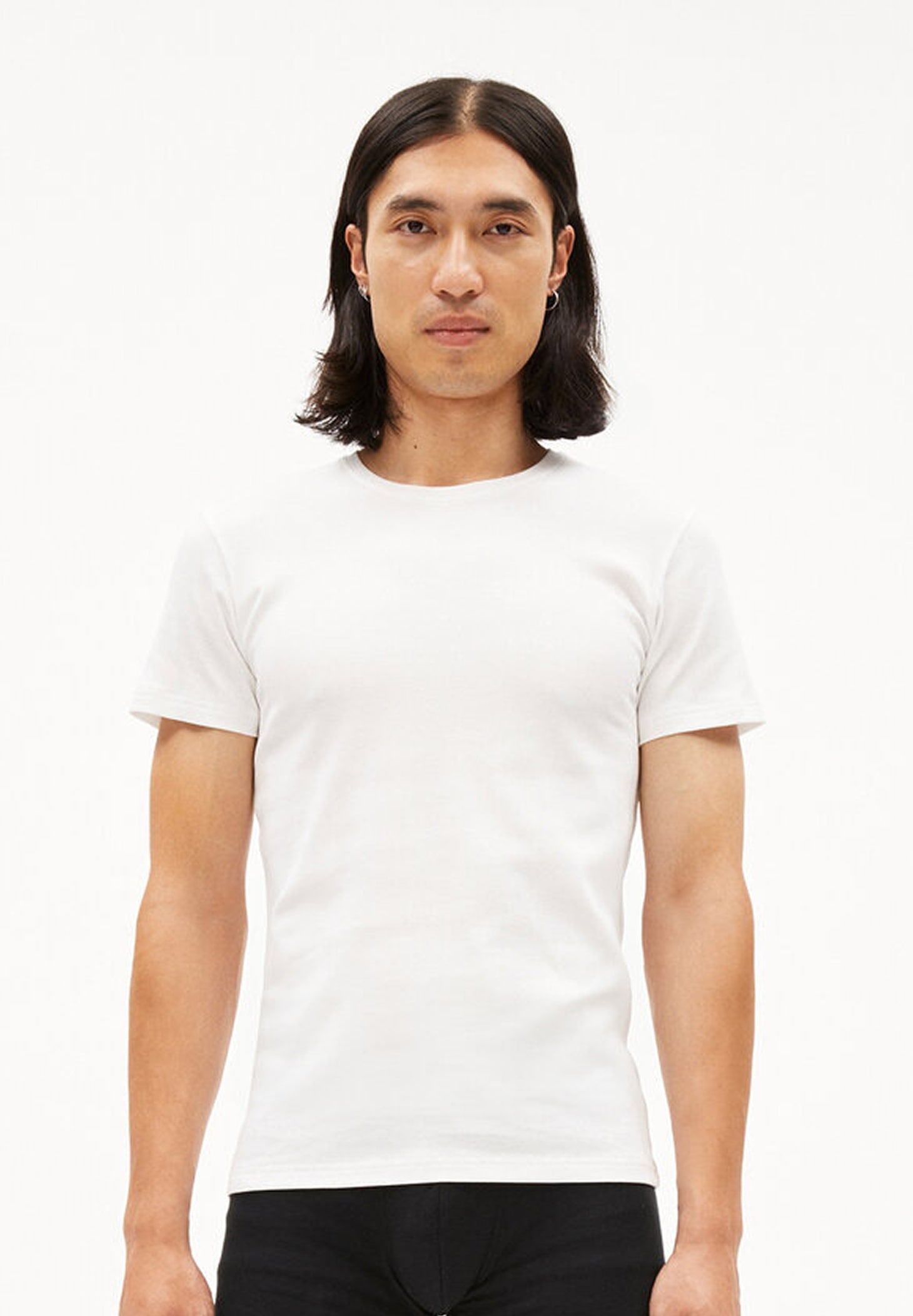 Person trägt weißes T-Shirt HELMAAR RIB im Slim Fit mit geripptem Stoff und schwarze Hose, frontal aufgenommen vor weißem Hintergrund.