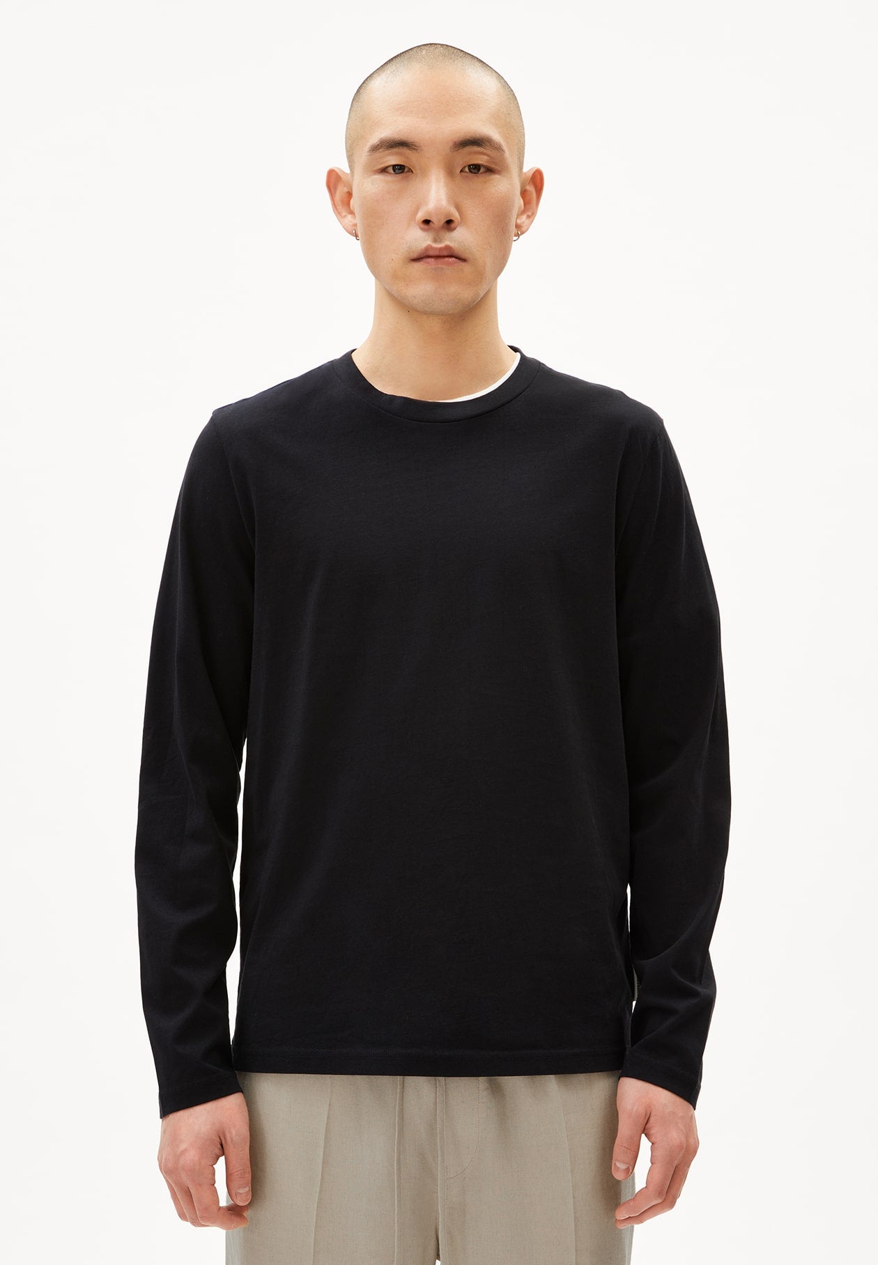 Mann trägt JAAMES LONGSLEEVE T-Shirt in Schwarz. Er guckt gerade aus und trägt zusätzlich eine beige Hose.