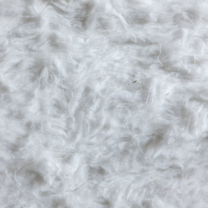 Nahaufnahme von weichen, weißen Textilfasern mit flauschiger Struktur.