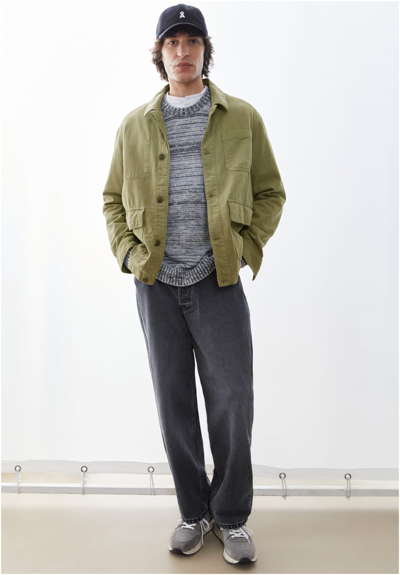 Model mit einer grünen Jacke und grauer Jeans