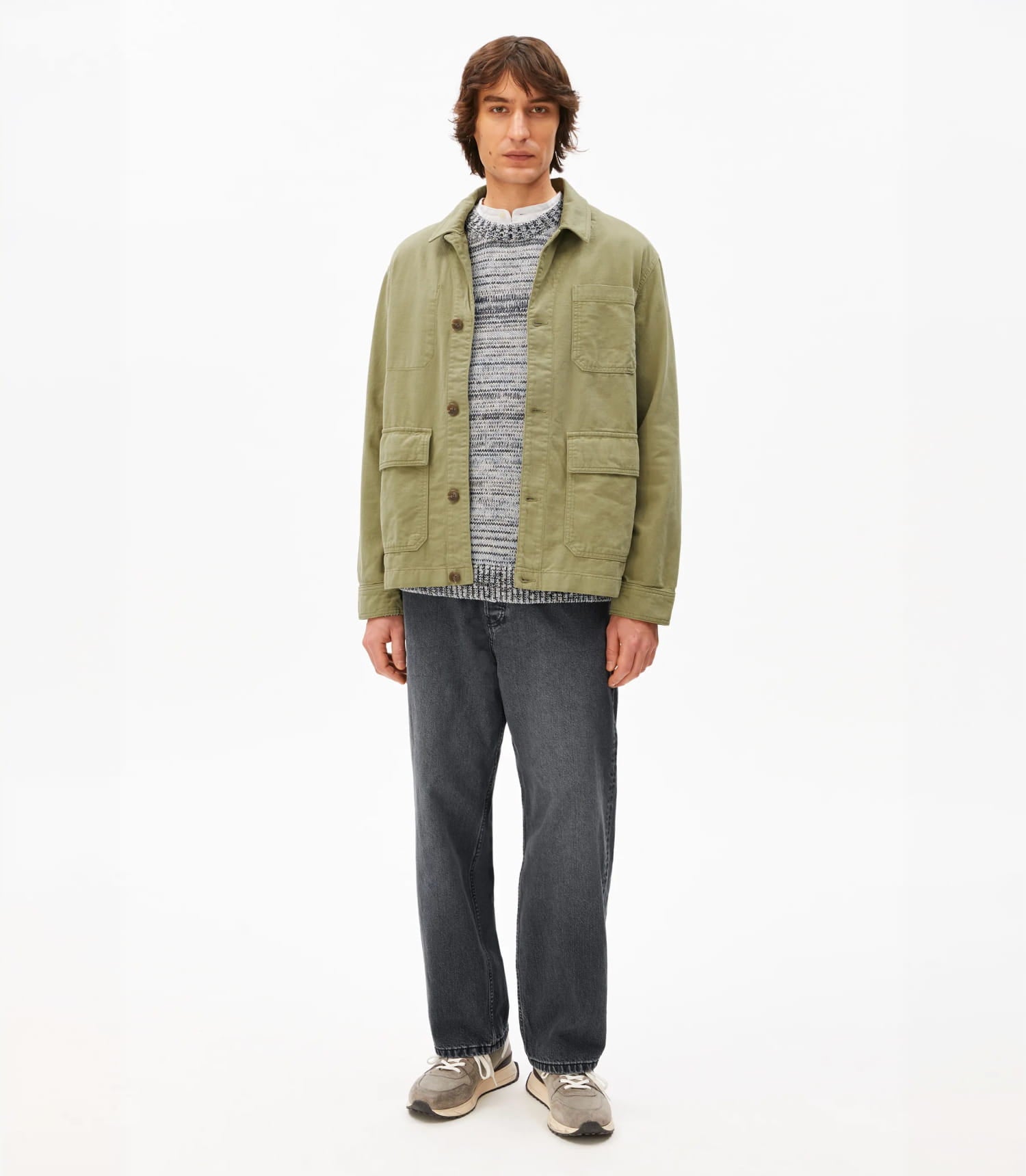 Model mit einer grünen Jacke und grauer Jeans