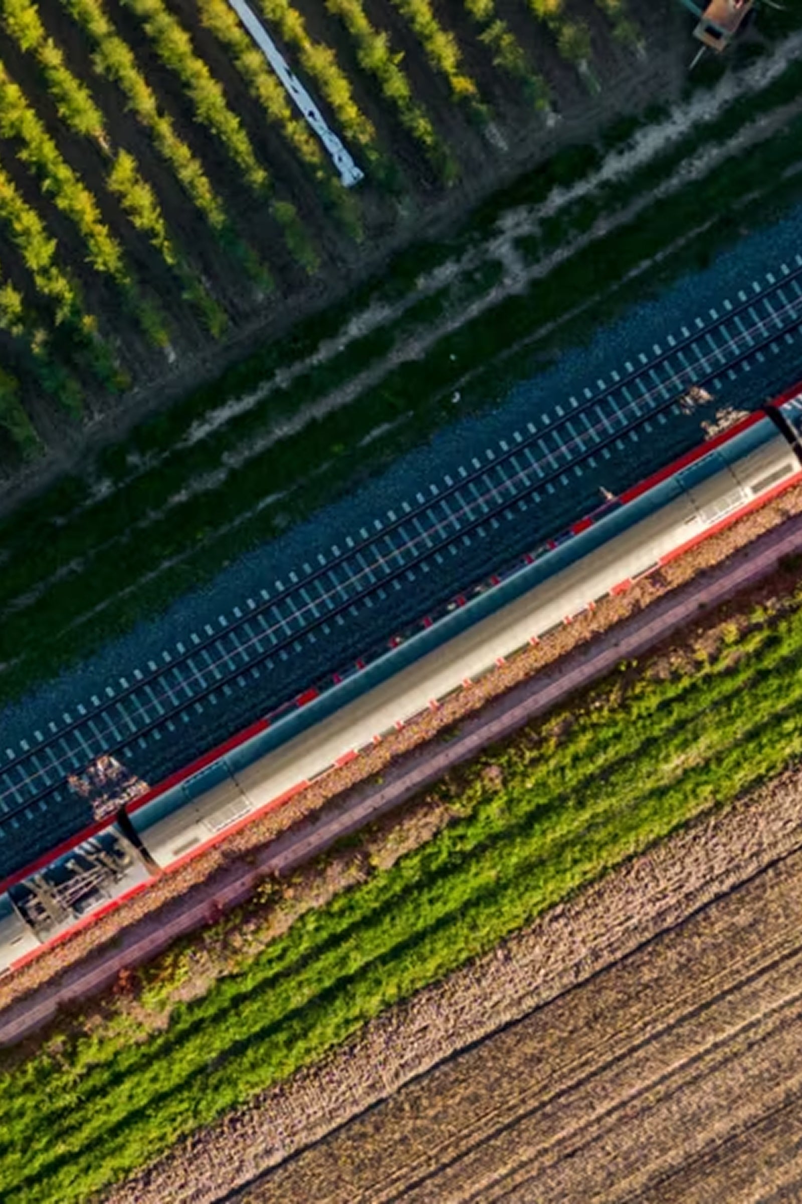 Bahngleisen von oben zu sehen mit verschieden Grunflächen. Klicke hier um mehr über Reiseziele mit der Bahn zu erfahren